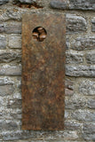Bronze rust-colored metal plaque sculpture with a circular cutout with birds on a stone wall