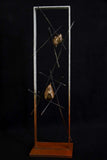 Bronze sculpture of two wren birds in a large frame surrounded by small branches on a black background.