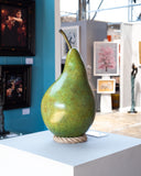 Large decorative pear sculpture on a pedestal in an art gallery setting.