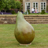 Large sculpture of a pear in a garden setting with a building in the background