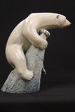 Carved bronze sculpture of a polar bear climbing a rock 