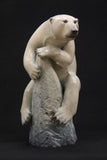 Bronze sculpture of a polar bear climbing a rock on a black background