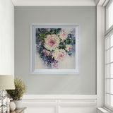 Framed floral painting on a gray wall with a window and lamp in the background
