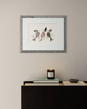 Framed artwork of three stylized fish on a wall above a console table with a candle and books.