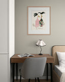 Small home office with a desk, chair, lamp, and framed artwork on the wall.