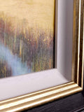 Corner of artwork of a vibrant yellow meadow with white moulding and a gold and black frame