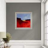 Framed landscape artwork with red and blue colours on a grey wall.