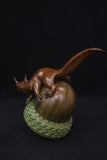 Bronze sculpture of a squirrel on an acorn against a black background