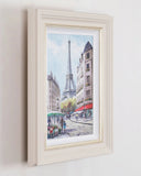 Framed artwork of a Parisian street scene with the Eiffel Tower.