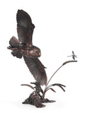 Bronze sculpture of an owl in flight with a dragonfly on a white background