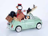 A decorative miniature car figurine in mint green, styled with plush toys and travel accessories. The car features 'Doug Hyde' script on the side door and is set against a seamless white studio background.