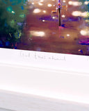 A close-up of a framed art print with a white mat and a colorful impressionistic painting depicting a cross in a garden. Handwritten text on the white mat reads 'Good times ahead' with a smiley face.