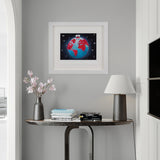 Framed artwork of a colorful globe on a gray wall above a small table with decor items.