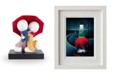 Two figurines, one with a red hood and blue scarf, next to a framed artwork of a red flower in a dark setting.
