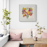 Living room with a floral painting above a sofa, plants on either side, and a small table.