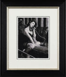 Framed black and white artwork of a woman on the phone with a man in the background.