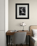 Small desk with chair, lamp, and framed picture on a wall in a room.