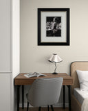 Small desk with chair, lamp, and framed picture on a wall in a room.