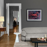 abstract oil painting of red horse on a dark background with a black and gold frame on wall above grey sofa and wooden table.