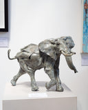 Bronze sculpture of an elephant on a white pedestal against a light background