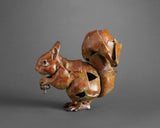 Sculpture of a squirrel holding a nut on a gray background