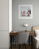 Small home office with a desk, chair, lamp, and framed picture on a gray wall.