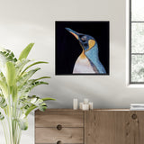 Framed artwork of a penguin on a wall above a wooden cabinet with candles.