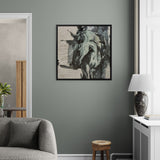 Living room with a gray wall, framed artwork, gray sofa, wooden stool, and lamp.