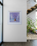 Framed artwork on a wall in a modern interior setting with a staircase and plants.