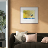 Framed artwork of two birds over water on a wall above a sofa with decorative pillows.