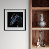 Framed artwork of dark horse on a black background on a white wall next to wooden shelves.