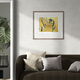 Framed artwork of birds on a yellow background above a sofa with decorative pillows.