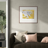 Framed artwork of birds on a yellow background above a brown sofa with patterned cushions.