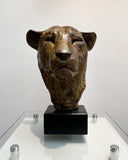 Bronze sculpture of a bear head on a black base against a white background