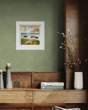 Framed artwork on a green wall above a wooden shelf with decorative items.