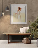 Framed artwork of a woman in a white dress on a wall above a wooden bench with pillows and a basket.
