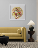 Framed artwork of a woman with flowers on her head above a yellow sofa in a living room.