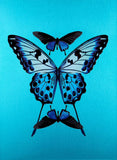 An art print featuring three blue and black butterflies arranged symmetrically on a bright turquoise background.