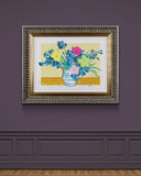 ornate framed artwork pink,yellow and green iris flowers in a white and blue vase with the text follow your dreams, vincent, set against a yellow background with paint splatters on a purple gallery wall