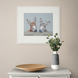 framed donkey artwork on cream wall above wooden sideboard