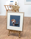 Framed picture of a dog on a decorative gold easel.