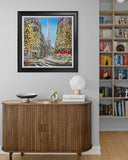 Framed artwork of a city street scene above a wooden cabinet with decorative items.