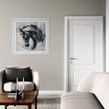 monochrome painting of side profile of dark horse framed in white on plain wall above armchair.