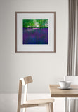 Framed artwork of a forest scene with purple flowers on a wall above a dining table.