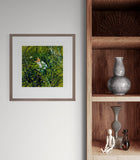 Framed artwork on a wall next to a wooden shelf with decorative items.