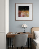 Small home office with a desk, chair, lamp, and framed artwork on a gray wall.