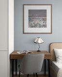 Small home office with a desk, chair, lamp, and framed artwork on a light blue wall.