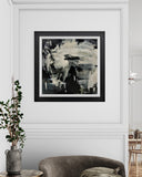 Abstract black and white painting in a modern interior setting with a chair and plant.