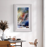 Framed mountain landscape painting on a wall above a dining table.