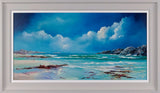 Framed artwork of a beach scene with blue sky, white clouds, and rocky shoreline.
